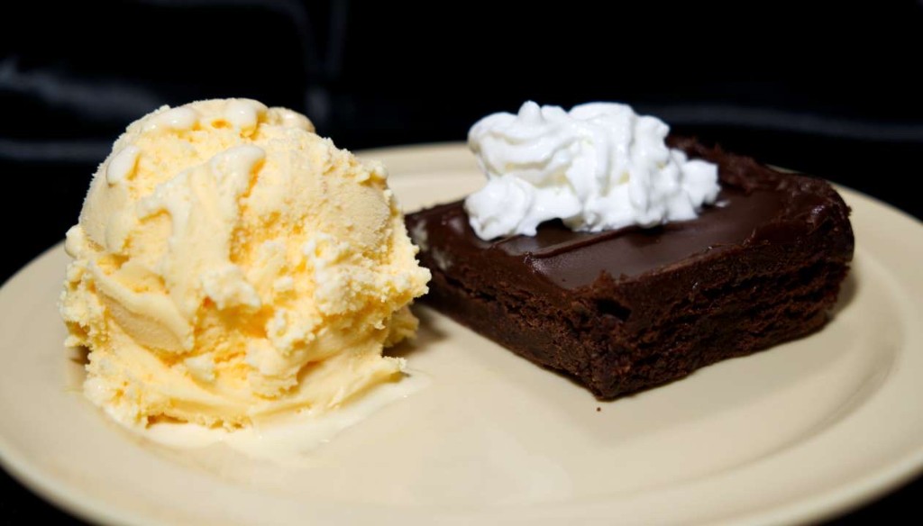 Vanilla ice cream beside a chocolate brownie with whipped cream