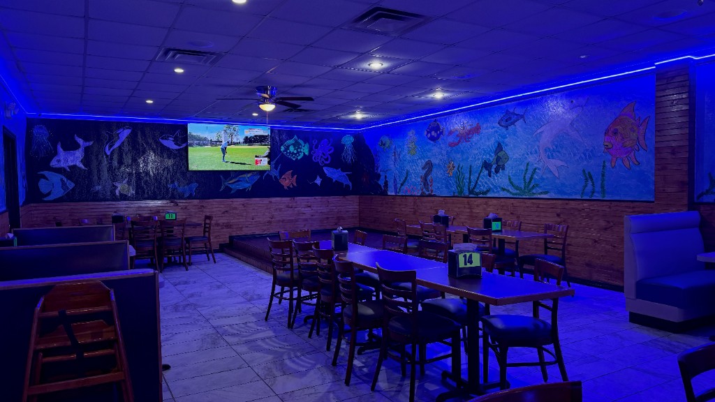 A dining table in the room, with the sea mural and wood chairs
