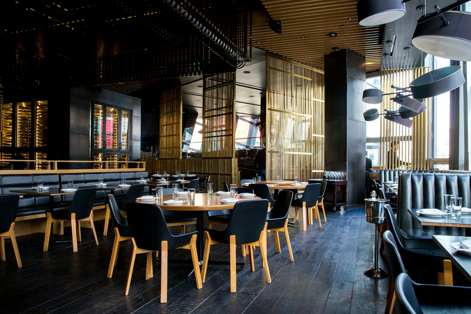 A dark dining room with black chairs and warm light