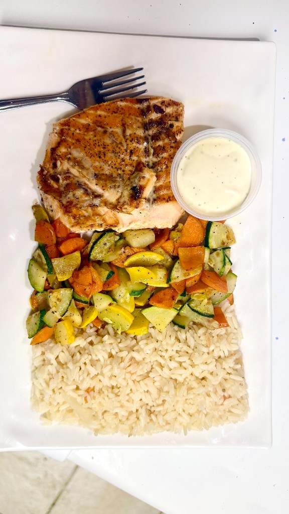 Grilled salmon with rice, vegetables, and a cream sauce