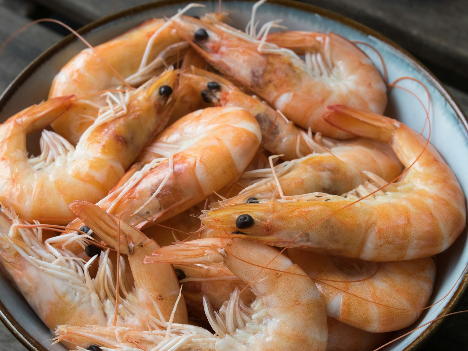 A bowl of cooked shrimp on a wooden table