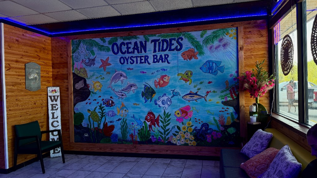 The Ocean Tides mural in the front room, with fish, dolphins, and a welcome sign
